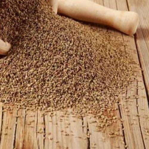a pile of Ajwain (Carum Copticum) grains on a wooden surface
